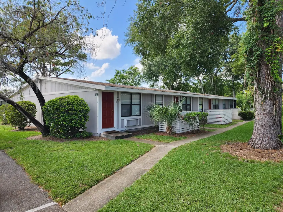 Single-story apartment homes beneath mature trees at Heatherwood in Kissimmee, Florida.